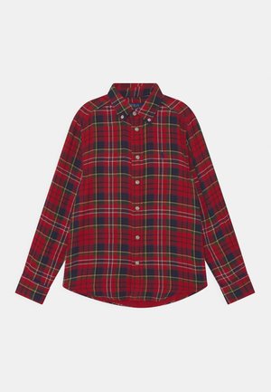 Camisa de cuadros en rojo, verde y azul marino con mangas largas, cuello con botones y botones beige, extendida sobre un fondo blanco.