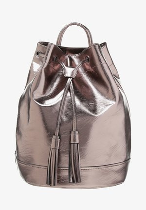 Metaliczny plecak w kolorze różowego złota z zamknięciem na sznurek, dwoma dekoracyjnymi frędzlami i gładką, błyszczącą fakturą. Okrągły kształt z krótkimi uchwytami.