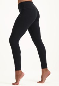 Svarta leggings med bred midjeband, åtsittande design och ankle cuffs. Tillverkade av ett mjukt, stretcht tyg för enkel rörelse.