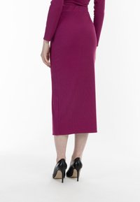 Figurbetontes, magentafarbenes, geripptes Midikleid mit glattem Textur, seitlichen Schlitzen und schmalem Bund, kombiniert mit schwarzen Stiletto-Heels.