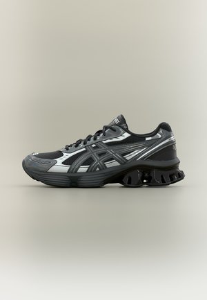 Scarpa da corsa ASICS nera e grigia con pannelli in mesh, allacciatura frontale e suola ammortizzante unica su sfondo neutro.