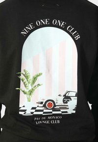 Černá mikina se symbolem znázorňujícím bílý vůz, květináč a pozadí v pastelových pruzích. Text obsahuje "NINE ONE ONE CLUB" a "PAS DE MONACO LOUNGE CLUB."