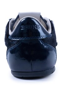 zapatilla azul marino con acabado de charol brillante y acentos de piel de textura, con un collar acolchado y un logotipo en relieve en el talón.