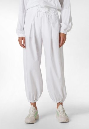 Weiße, locker sitzende Hosen mit einem elastischen Bund und Bündchen. Hergestellt aus leichtem Material und mit dezenten Falten an der Vorderseite.