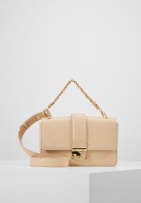 Beige handväska med krokoprägling och guldfärgad hårdvara, en framflik och axelrem med kedjedetaljer. Utrustad med en säker låsning.