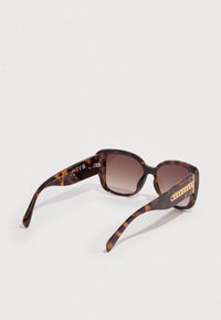 Γυαλιά ηλίου με σκελετό σε αποχρώσεις χελώνας και φακούς με καφέ βαθμιδωτό χρώμα, διακοσμημένα με χρυσές αλυσίδες στα πλάγια και σχεδιασμό με τετράγωνο πλαίσιο.