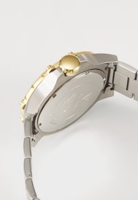 Stainless Steel Uhr mit einer vergoldeten Lünette und Krone. Das Armband verfügt über gebürstete und polierte Glieder. Runder Gehäuse mit einer glatten Rückseite.