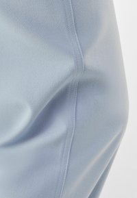 Light blue fabric with a smooth texture, displaying soft folds and a seam detail. The material appears lightweight and drapes gently.
