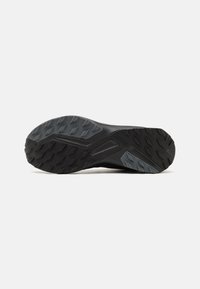 Sole di scarpa da ginnastica nera con suola in gomma testurizzata, caratterizzata da un motivo geometrico per la trazione e supporto laterale rinforzato.