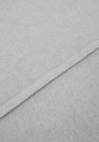 Lichtgrijs textiel met een geweven structuur, met een naad langs één rand en een gladde afwerking, met subtiele kleurvariaties.