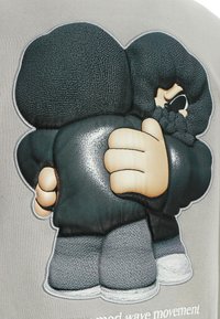 Tela gris con un diseño bordado de dos figuras de dibujos animados en ropa oscura abrazándose, con detalles texturizados y acentos de color claro.