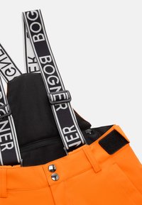 Světlé oranžové overaly s nastavitelnými černými popruhy, na kterých je bílé logo "BOGNER". Obsahují černé látkové a stříbrné kovové detaily.