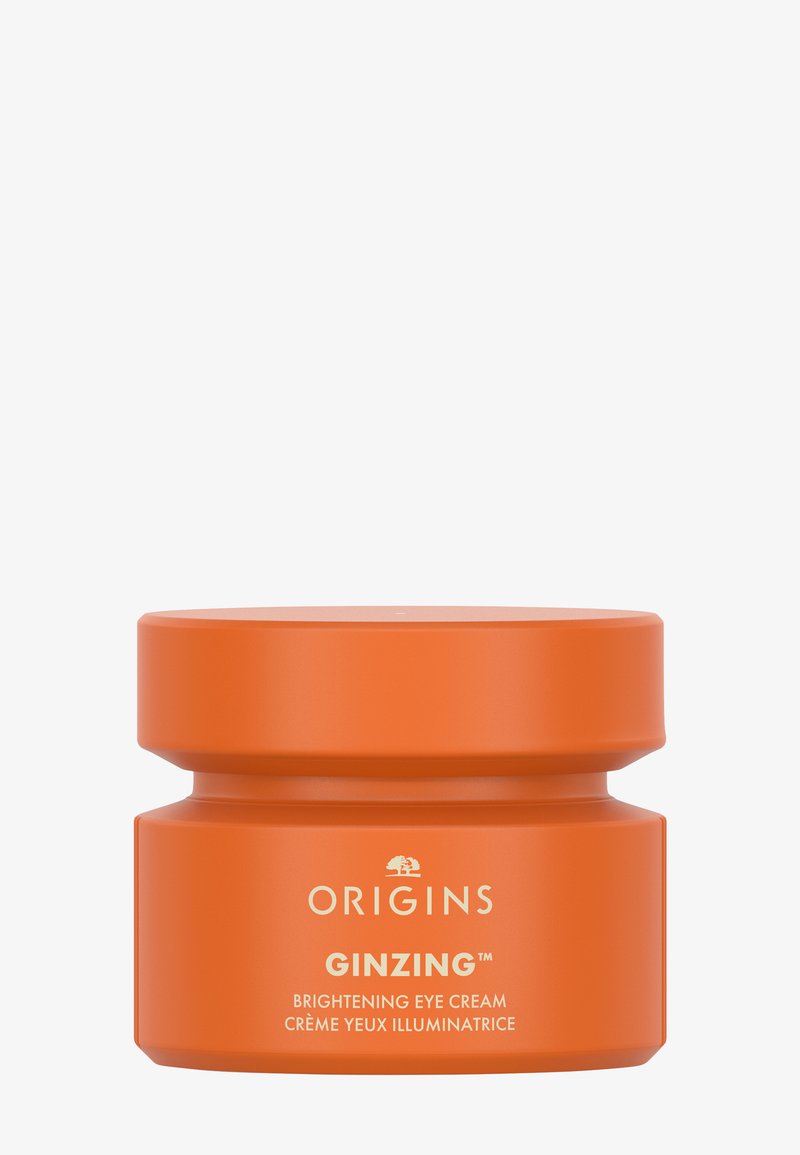Contenitore circolare arancione della crema occhi illuminante Origins Ginzing. Finitura opaca liscia, etichetta bianca con dettagli del prodotto.
