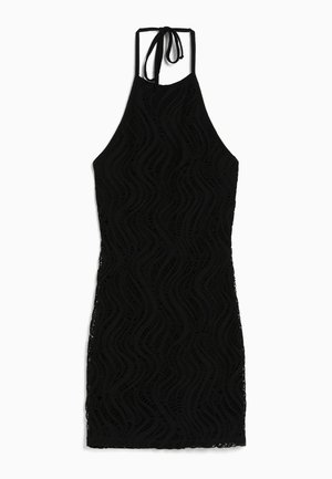 Robe noire à encolure halter avec un motif de vagues texturé, coupe ajustée et longueur mini. Associée à des sandales noires chunky avec un détail de boucle.