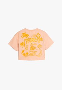 Perzik geknipte T-shirt met gele tropische graphic, met palmbomen, fruit en tekst die "Tropisch Paradijs" en "Eindeloze Zomer" leest.