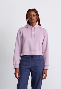 Haut de hoodie court violet clair avec capuche à cordon et logo blanc sur la poitrine, associé à un pantalon cargo bleu marine à taille élastique.