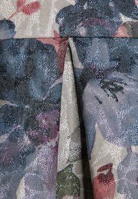 Tkanina w kwiaty z mieszanką niebieskich, fioletowych i różowych odcieni z błyszczącymi akcentami. Fala tekstury dodaje głębi całkowitemu wzorowi.