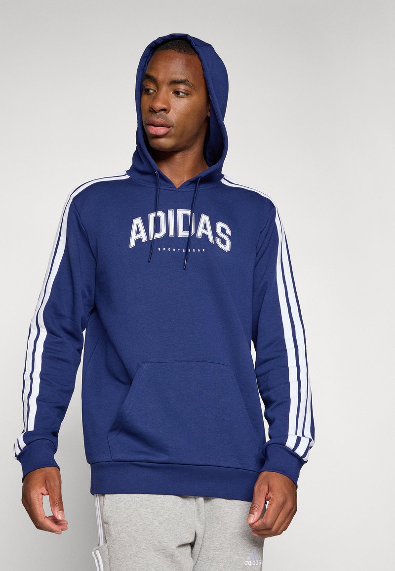 Marineblauwe capuchontrui met wit Adidas-logo, kangoeroezak en witte strepen langs de mouwen; zachte stof en relaxed fit.