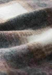 Uldent stof med en blød tekstur har et ternet design i nuancer af grå, brun og creme, med varme toner og et hyggeligt udseende.