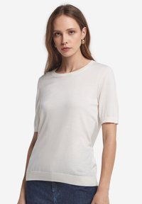 Hvid kortærmet pullover med rund krave, ribbede manchetter og kant, lavet af et blødt, let stof.