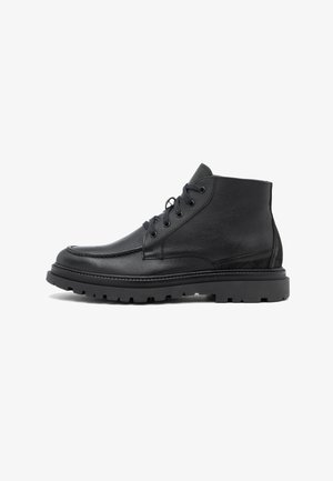 Bottines noires en cuir avec une finition texturée, bout rond, lacets et semelle crantée en caoutchouc épais pour une meilleure adhérence.