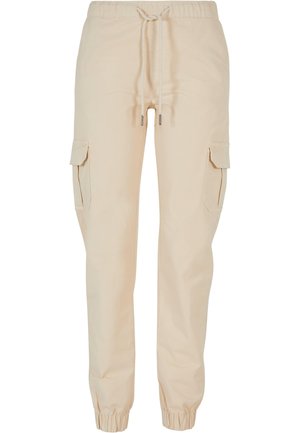 Pantalons cargo beiges en coton, avec une taille élastique à cordon de serrage, des poignets fuselés et des poches latérales. Texture lisse.