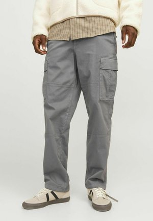 Gray cargo pants featuring multiple side pockets, stitched detailing, and a relaxed fit, paired with beige sneakers with black accents.