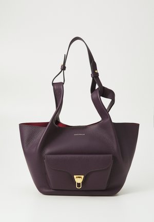 Sac fourre-tout en cuir violet avec une finition texturée, doté d'une poche avant et de quincaillerie dorée. Doublure intérieure rouge. Deux bretelles pour l'épaule.