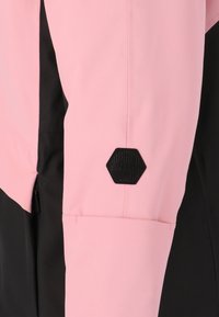 Rosa und schwarze Skijacke mit einem sechseckigen schwarzen Logo am Ärmel, glattem Stoff mit auffälliger Farbblockierung und einer Reißverschlusstasche.