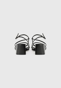 Svart strap sandaler har en blokks�åle, flere tynne stroppar og en glatt finish. Designet er åpent foran med en minimalistisk estetikk.