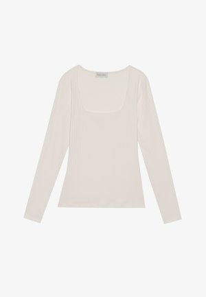 Langermet, ribbet topp i off-white med firkantet halsutskjæring. Myk tekstur og tettsittende design, med en tag merket "ANNA FIELD."