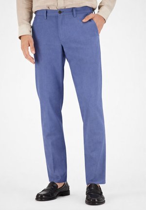 Pantaloni da uomo blu a taglio dritto con tasche frontali abbinati a mocassini in pelle nera e camicia beige.