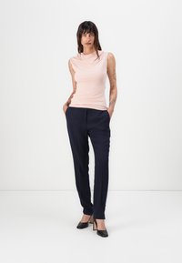 Růžový top bez rukávů s volným výstřihem, kombinovaný s tmavě námořnickými, padnoucími kalhotami. Model má na sobě černé lodičky. Jednoduchý, čistý design.