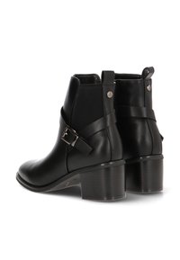 Botas de cuero negras hasta el tobillo con un tacón grueso, con un acento de hebilla y paneles laterales elásticos, diseño elegante. Textura suave.