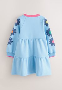 Světle modré šaty s dlouhým rukávem a vrstvenou sukní, tmavě modré květinové záplaty s barevnými středy na rukávech a růžový žebrovaný límec a manžety.