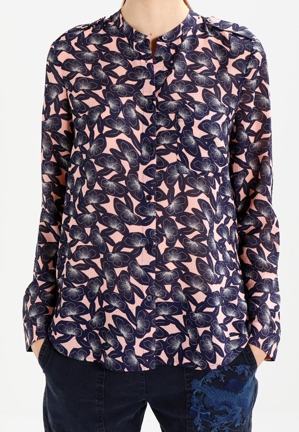 Långärmad blus med ett marinblått blommönster på en ljusrosa bakgrund, med mandarin-krage och knäppning.