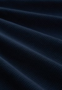 Teksturowana, granatowa tkanina o splocie w formie wzoru, z miękkimi, falistymi fałdami i gładkim wykończeniem. Nadaje się do różnych zastosowań.