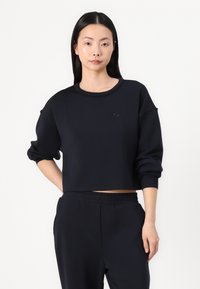Rövidített navy kék pulóver, puha anyagból, kerek nyakkivágással és eső vállakkal. Minimalista logó található a mellkason.