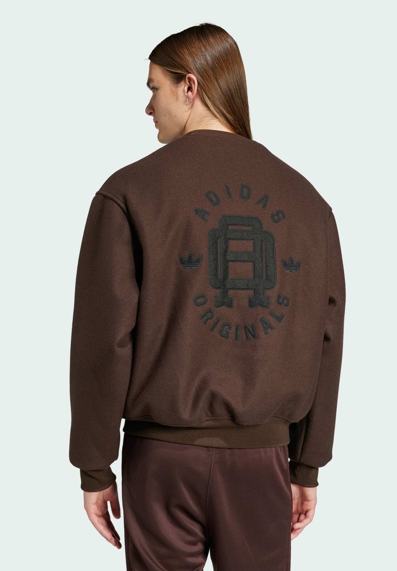 Brun sweatshirt med en afslappet pasform, der har et stort sort logo på ryggen, ribbede ærmer og talje. Blød struktur og afslappet stil.