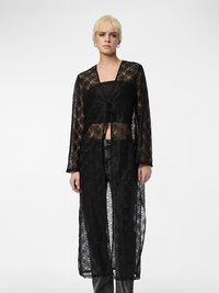 Cardigan lungo in pizzo nero con davanti aperto, caratterizzato da motivi floreali e maniche lunghe, indossato sopra una maglietta nera aderente e jeans.