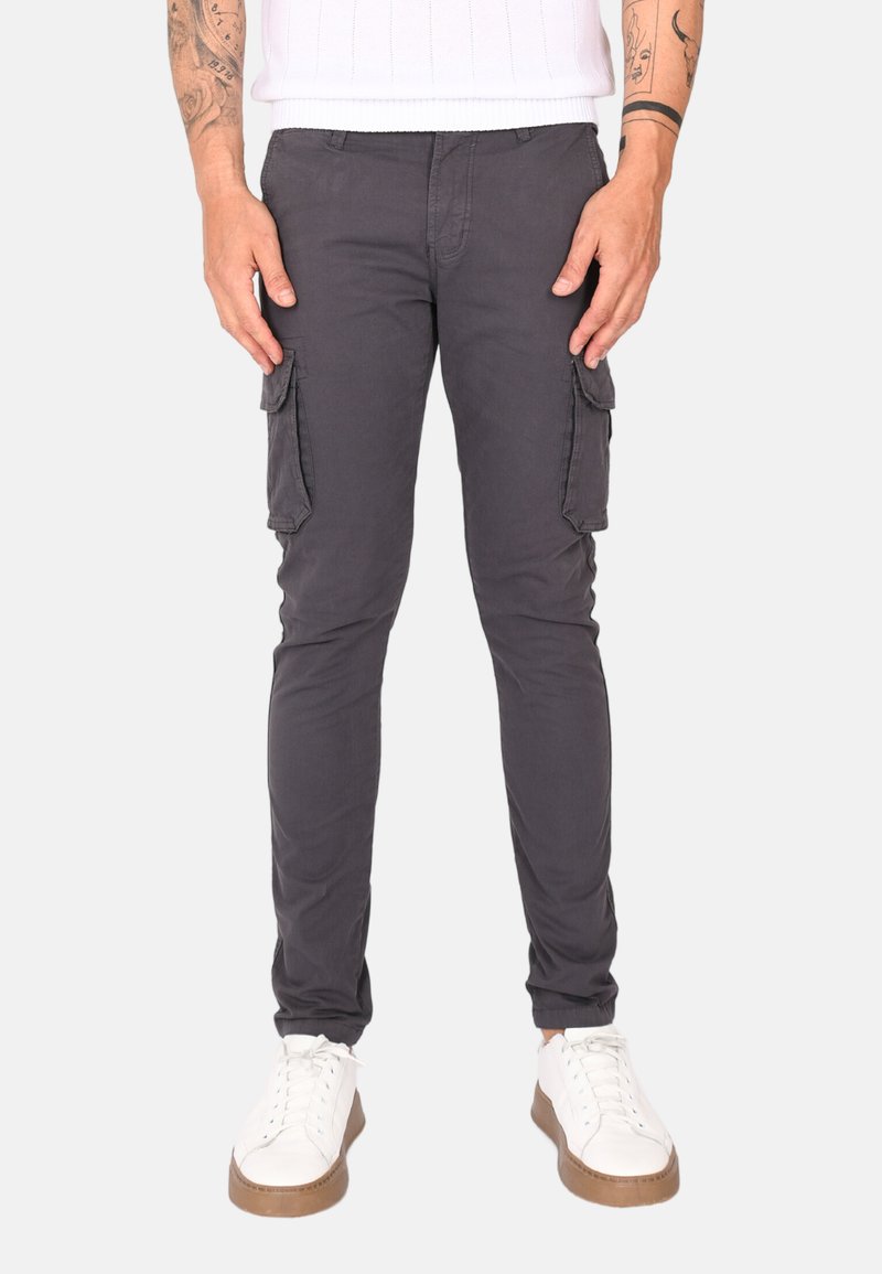 Pantaloni cargo grigi scuri, realizzati in cotone, dotati di due tasche laterali e una vestibilità slim. Abbinati a sneakers bianche con suola color tan.