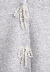 Cardigan en tricot gris avec des accents en perles en forme de nœuds sur le devant, fabriqué dans un tissu doux et texturé.