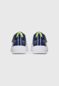 Pair of navy blue and white children's sneakers with neon green lining and gray Velcro straps shown from the back on a white background.