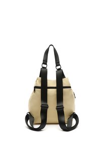 Zaino con corpo color crema, spallacci neri regolabili, texture liscia, dotato di una tasca con zipper sul retro e design minimalista.