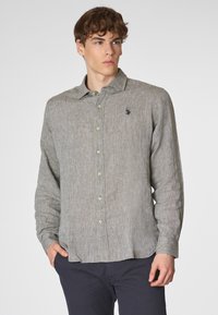 Camicia di lino grigio chiaro con colletto button-down, maniche lunghe e un sottile motivo tessuto. Presenta un piccolo logo ricamato sul petto.