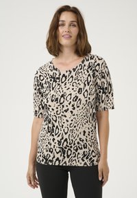 Beige short-sleeve top featuring a black leopard print pattern. Knit material with a round neckline and a relaxed fit.