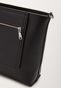 Schwarze Ledertasche mit strukturierter Oberfläche, Reißverschlusstasche vorne und silbernen Beschlägen. Kompaktes Design mit diskreten Ziernähten.