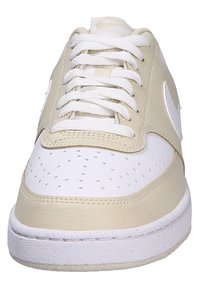 Zapatillas deportivas en blanco y beige con parte superior de cuero, puntera redonda, secciones perforadas y suela de goma texturizada con cordones.