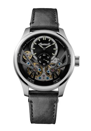 Montre automatique avec un bracelet en cuir noir, boîtier en acier inoxydable argenté, cadran transparent montrant des engrenages complexes et des accents noirs.
