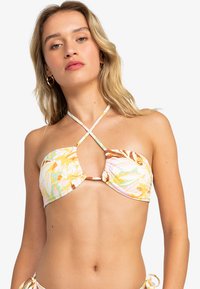 Bikini-top met bloemenpatronen in gele, muntgroene en bruine tinten, voorzien van een keyhole uitsnijding en gekruiste banden, gemaakt van een soepele stof.
